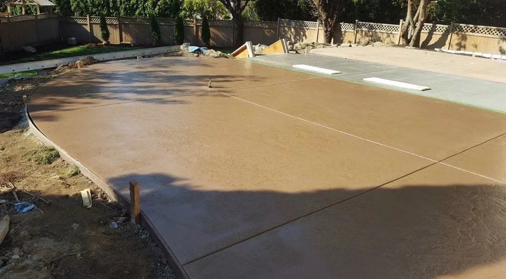 Curved brown stamped concrete patio being finished
