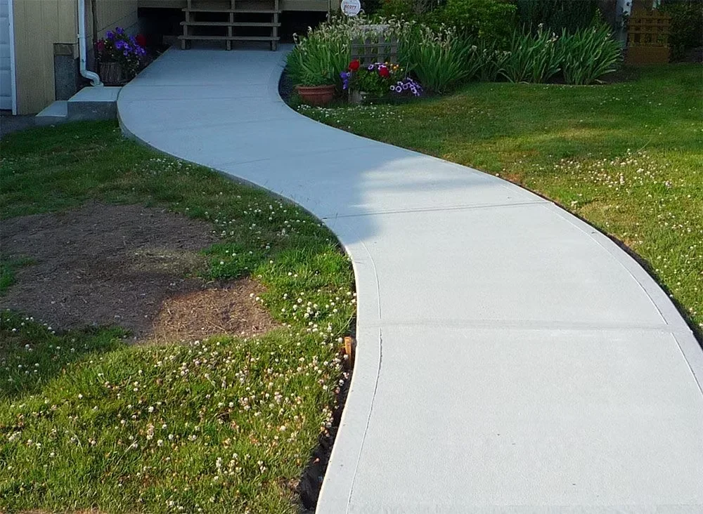 Curving smooth concrete walkway through a front lawn
