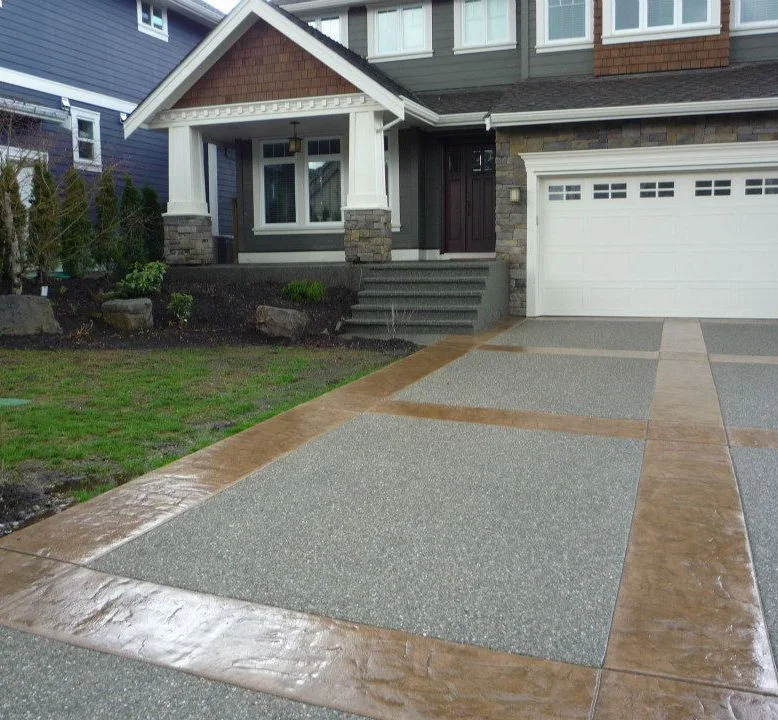 Exposed aggregate driveway with stamped coloured borders in front of a home