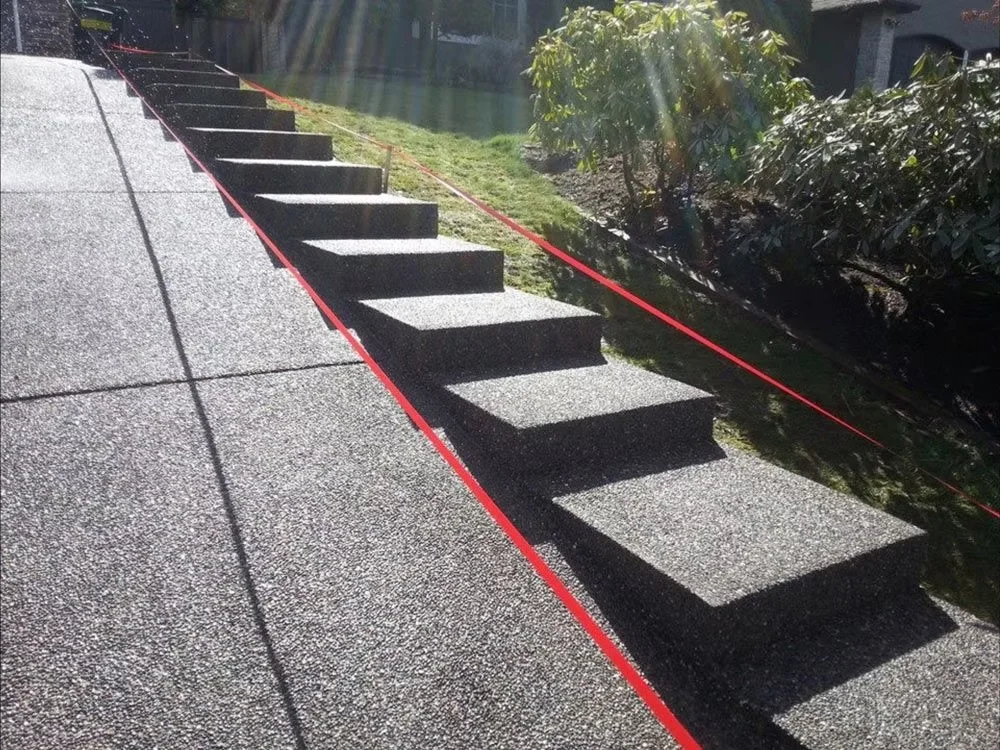 Exposed aggregate stairs beside a sloped garden
